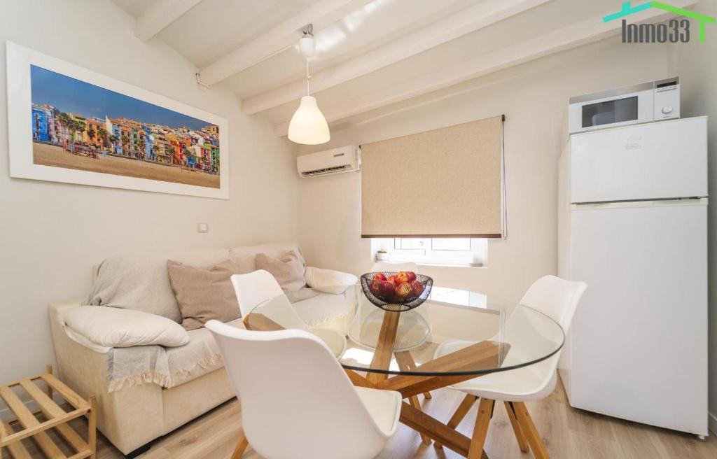 Una sala de estar con una mesa de cristal y sillas blancas. en Apartamento Sol del Mar, en Villajoyosa