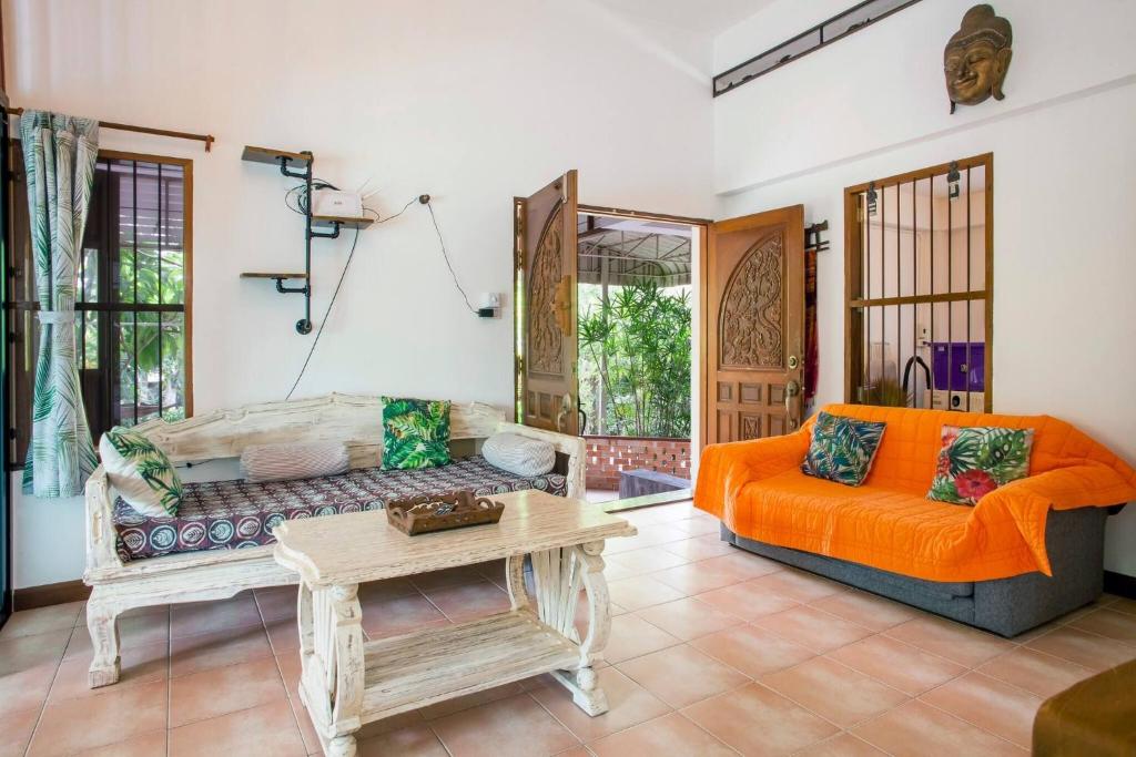 a living room with an orange couch and a table at Villa with private pool and mountain views in Ban Khlong Son