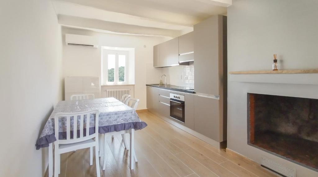 een witte keuken met een tafel en een open haard bij Casa Vacanze - Il Gelso in Collevecchio
