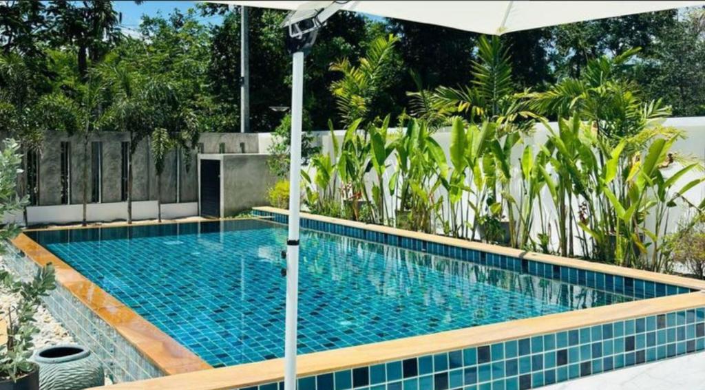 a swimming pool with an umbrella next to a swimming pool at Baan Suan pool valley Villa in Ban Nong Thale