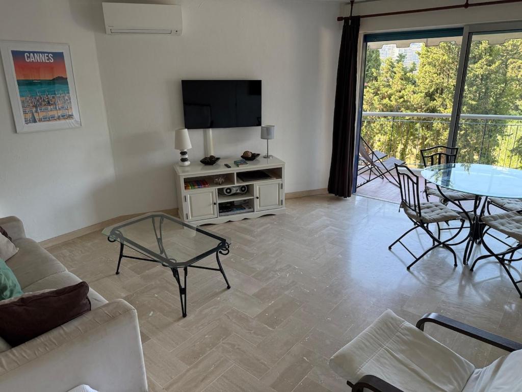 Una sala de estar con un sofá, una mesa y un televisor. en Beautiful F2 pool in Islette du Riou, en Mandelieu-la-Napoule