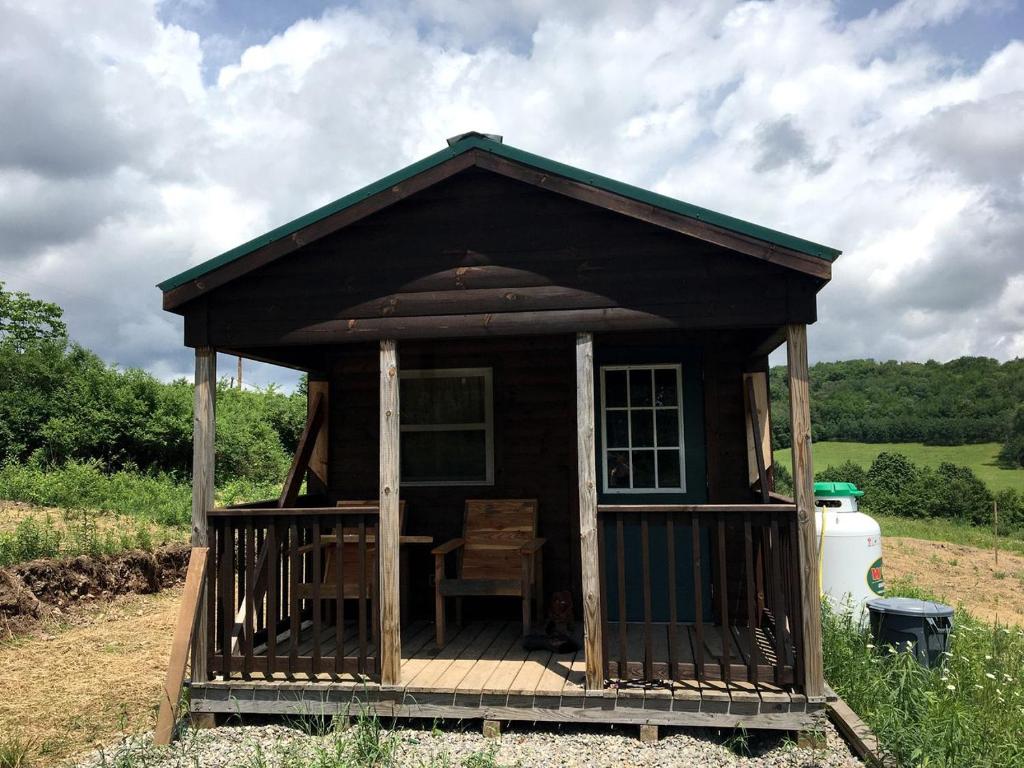 a small house with a chair on a deck at Galeton, Pennsylvania Glamping Cabin, Ideal for a Family Nature Escape in Short Run