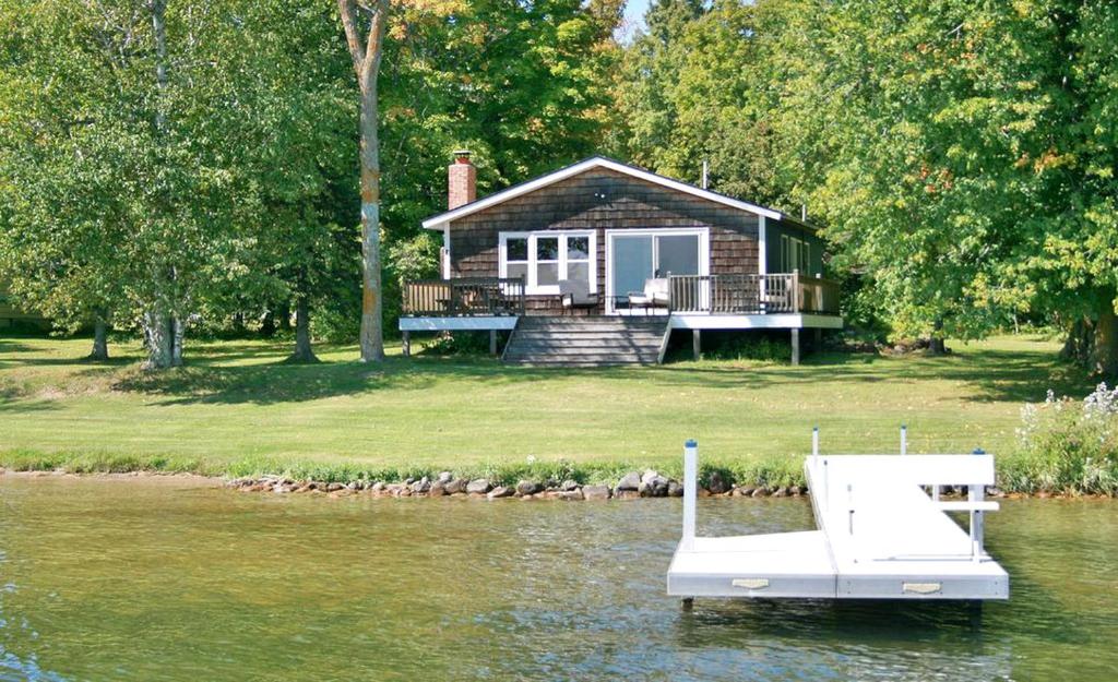 a house on the water with a boat in front of it at Family-Friendly Cabin Retreat on the Shores of Pokegama Lake, Minnesota in Grand Rapids