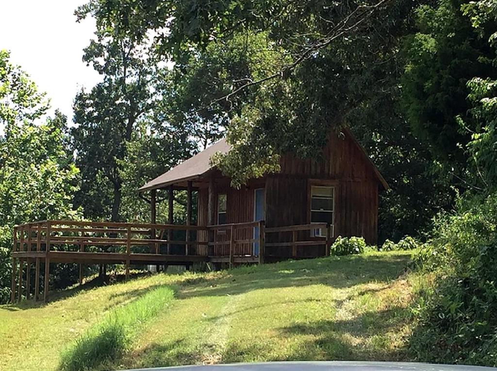 une petite cabane en bois sur une colline avec des arbres dans l'établissement Secluded Cabin on Organic Working Farm in the Ozarks of Northern Arkansas, à Maumee