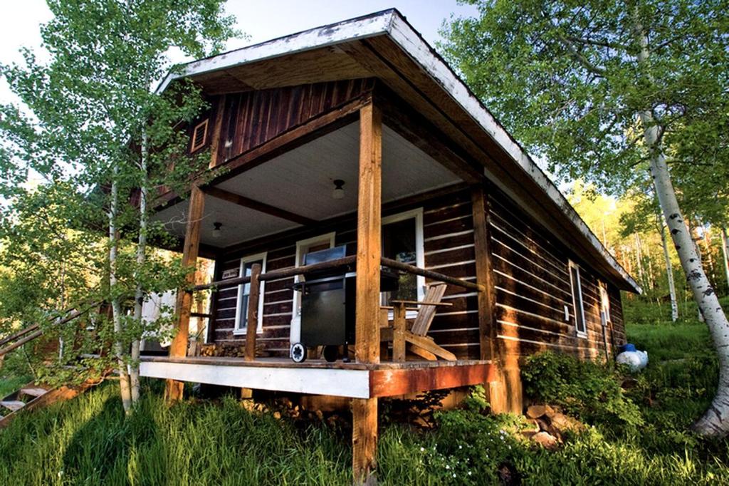 a log cabin in the woods with a porch at Quiet Mountain Cabin with Barbecue near Steamboat Springs in Colorado in Columbine