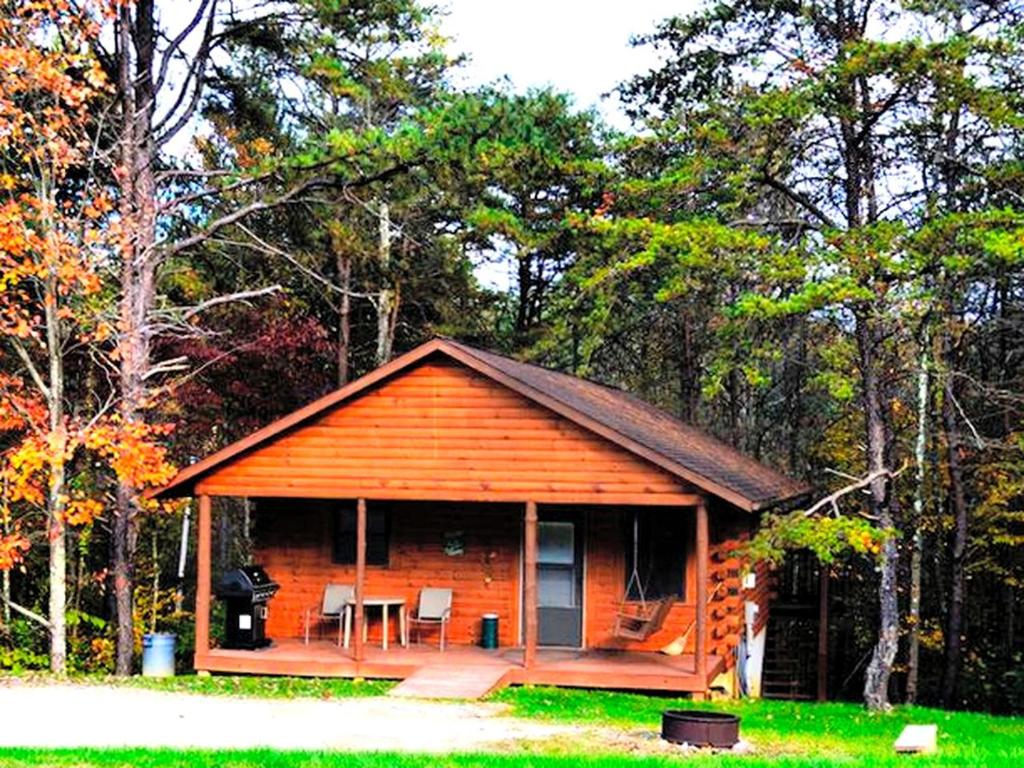 a cabin in the woods with a table and chairs at Cozy Log Cabin near Hocking Hills State Park, Ohio in Cedar Grove