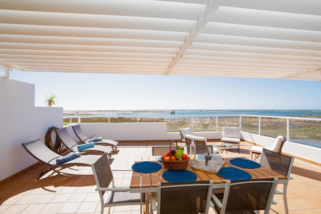 a dining room with a table and chairs and the beach at Brisa Da Ria Apartment, Formosa Village in Fuzeta