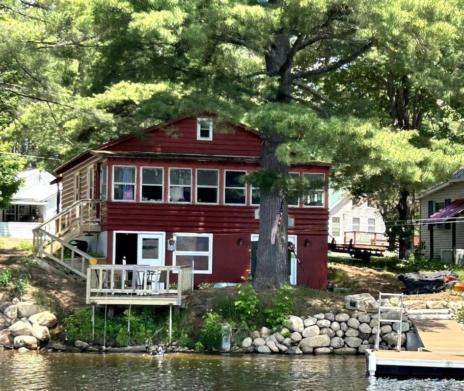 a red house on the shore of a lake at Cozy Lakefront Cabin Perfect for a Family Getaway in Wells, NY in Wells