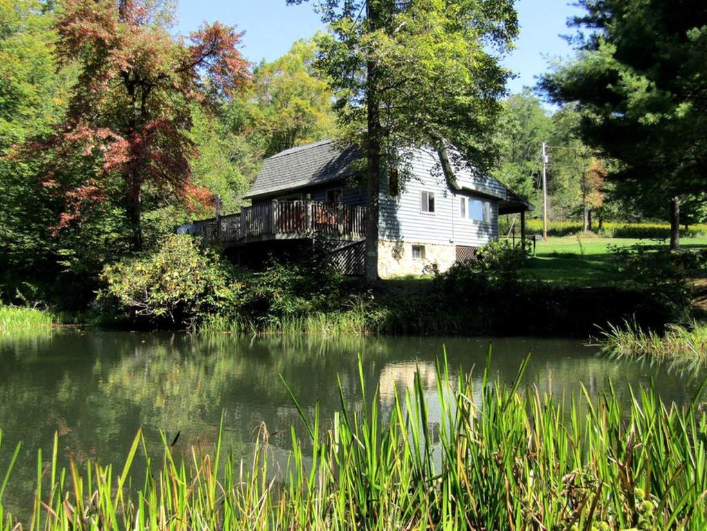 une vieille maison est située à côté d'un lac dans l'établissement Secluded Rental Cabin with Hot Tub near Deep Creek Lake in West Virginia, à Cranesville