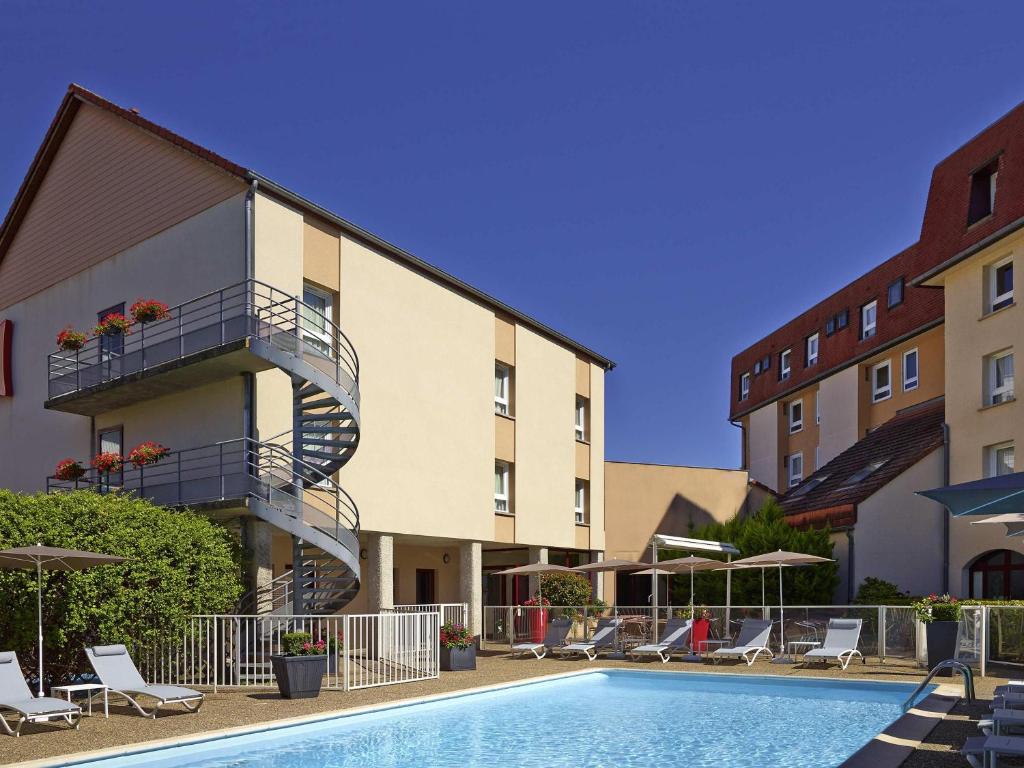 a hotel with a swimming pool in front of a building at ibis Beaune Centre in Beaune
