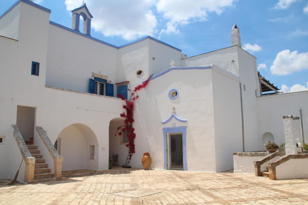 Masseria San Martino في بولينيانو آ ماري: كنيسة بيضاء فيها باب أزرق ودرج