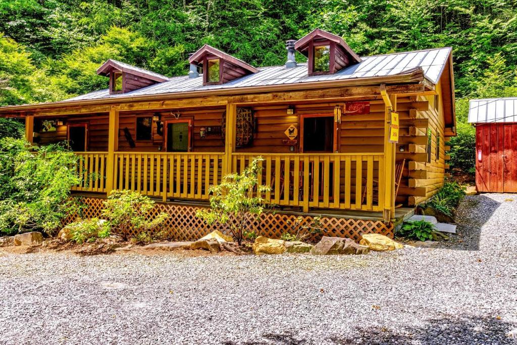eine große Holzhütte mit einer Veranda und einer Tür in der Unterkunft Cozy Creekside Cabin Rental near Cherokee, North Carolina in Cherokee