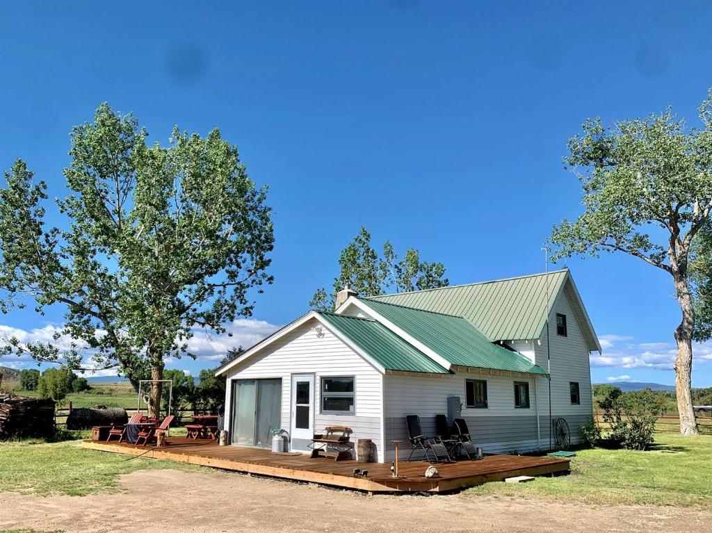 une maison blanche avec un porche et une terrasse dans l'établissement Stunning Cottage with Fire Pit in Saratoga, Wyoming, à Encampment
