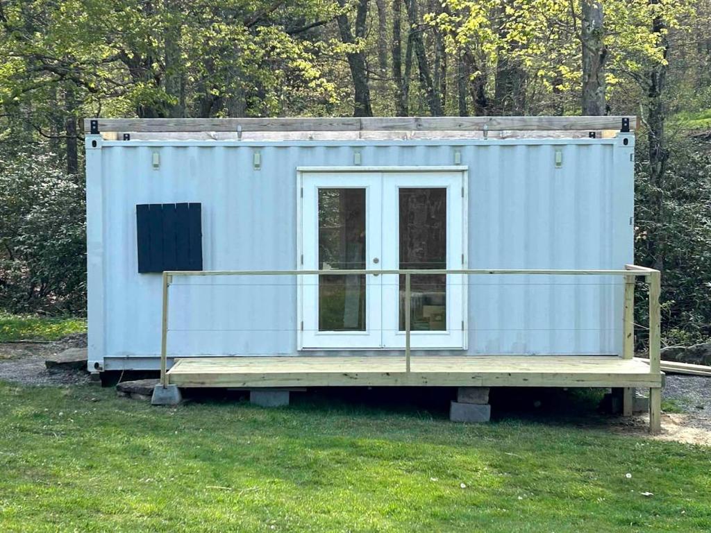 a blue tiny house sitting on a wooden platform at Friendsville Renovated Container Rental, for True Glamping Experiences in Maryland in Friendsville