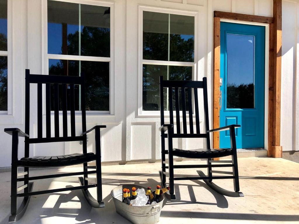 two black chairs sitting on a porch with a bowl of flowers at Charming Cabin for Glamping Vacations in Wimberley, Texas in Cloptins Crossing