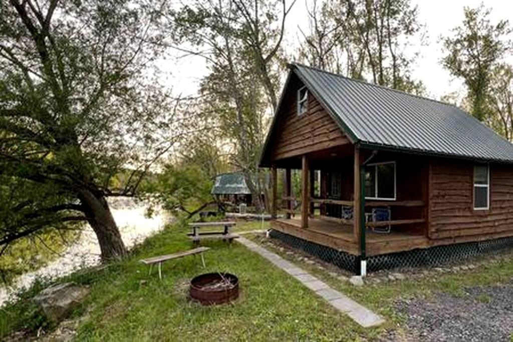 a wooden cabin with a picnic table and a bench at Secluded Riverside Cabin for 8 in Belfast, NY with Rustic Amish-Built Retreat in Oramel