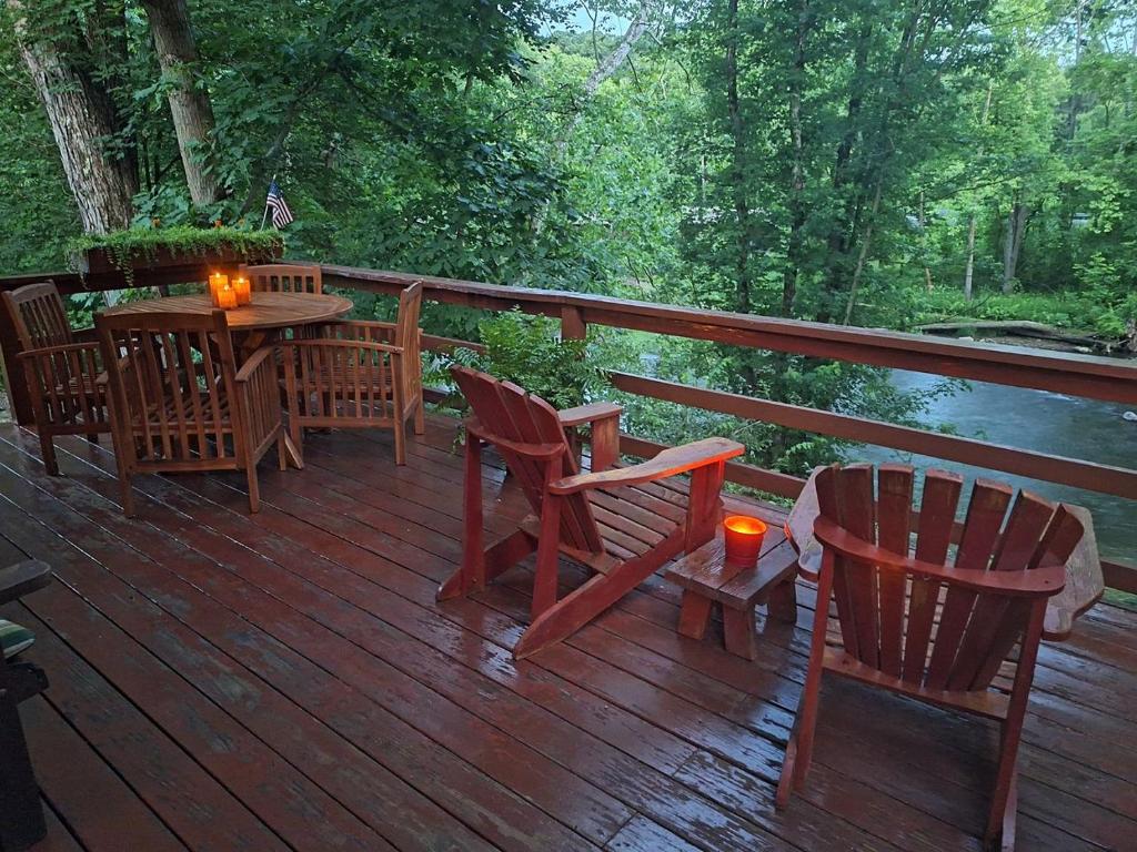 a wooden deck with chairs and a table with candles at Charming Creekside Log Cabin with Wood Burning Stove Overlooking the Neshannock Creek, Western PA in Volant