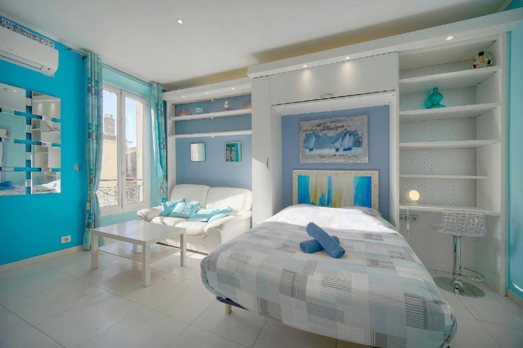 Un dormitorio con paredes azules y una cama y un sofá. en Studio Cannes Centre 2 min from La Croisette, en Cannes