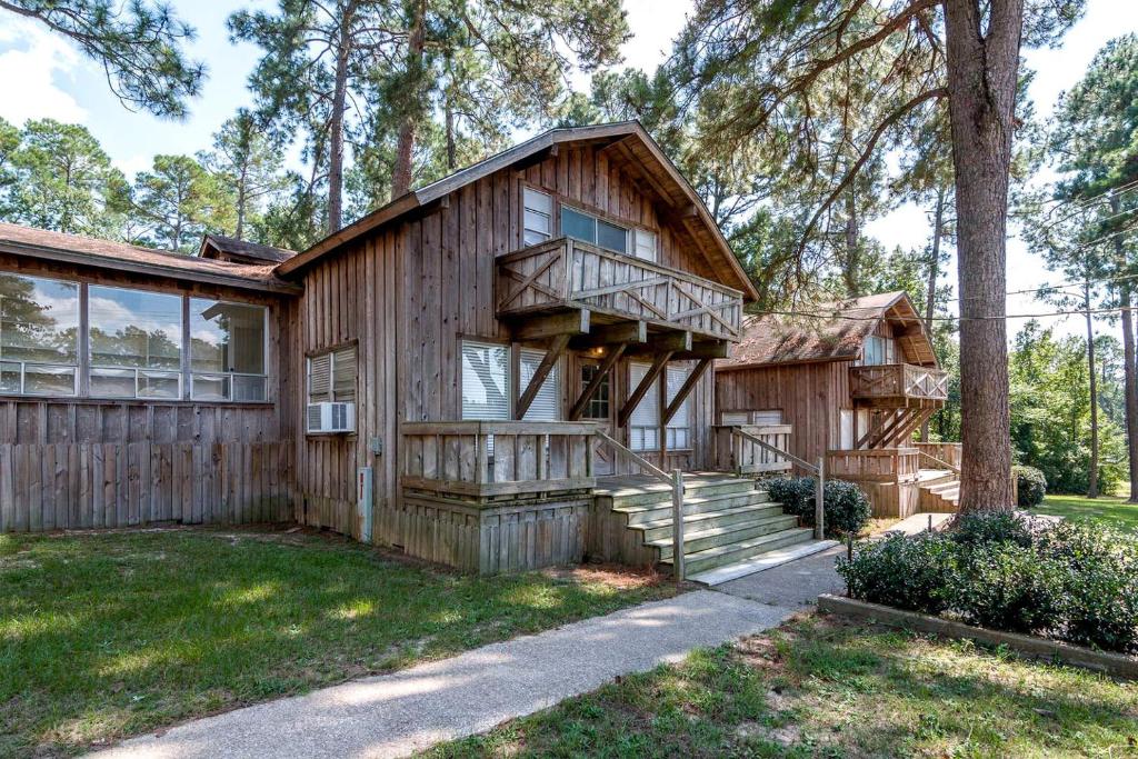 a log house with a porch and a tree at Gorgeous Log Cabin Rental near Nacogdoches for a Texas Family Vacation in Nacogdoches