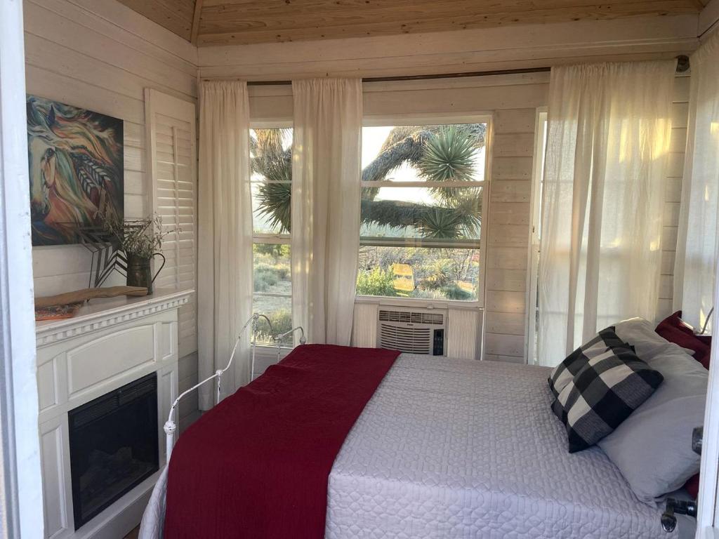 - une chambre avec un lit, une cheminée et 2 fenêtres dans l'établissement Charming Yucca Valley Cabin Rental for Getaways in California, à Yucca Valley