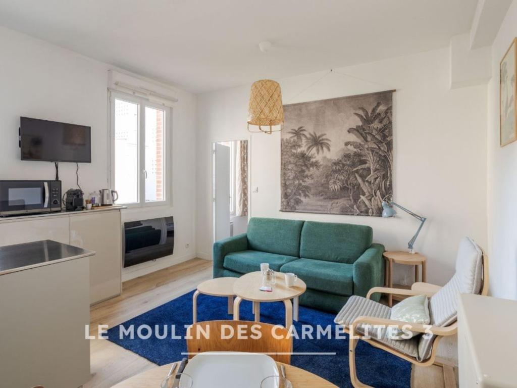 a living room with a green couch and a table at Les Carmélites - Appartements dans l'hyper-centre de Rennes in Rennes