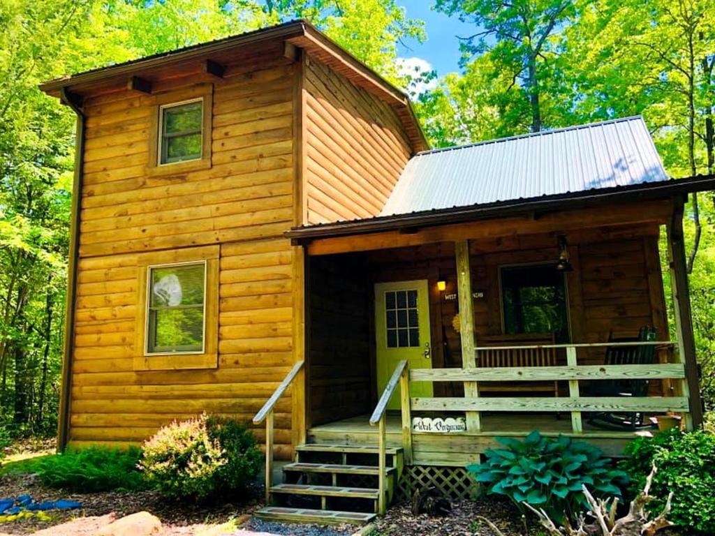 a cabin in the woods with a porch and stairs at Charming Cabin Rental in the Forest near Beckley, West Virginia in Hico