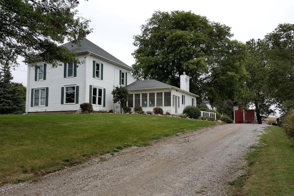 a white house with a dirt road in front of it at Comfortable Room Rental for a Vacation in Poweshiek County, Iowa in Montezuma
