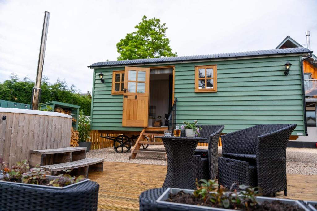 a green tiny house with chairs and a table at Driftwood with Hot Tub in Corpach