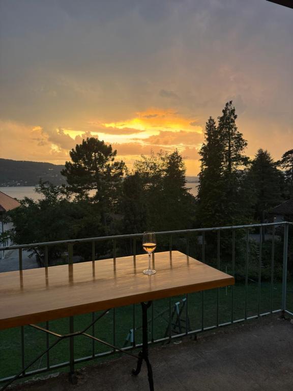 un bicchiere di vino seduto su un tavolo sul balcone di La-Villanelle - Magnifique vue sur le lac, 5 minutes à pied de la plage a Veyrier-du-Lac