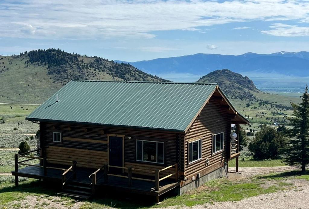 a log cabin with mountains in the background at Secluded Montana Cabin with Stunning Madison River Valley Views, Near Ennis, MT in Virginia City