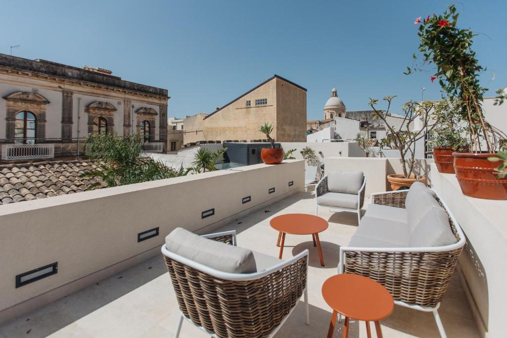 a rooftop patio with chairs and tables on a roof at Dimora Crocefisso in Noto