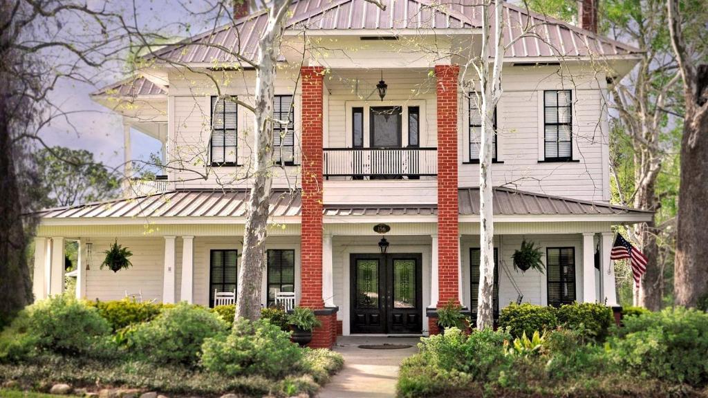 a white house with a flag in front of it at Luxurious Bed and Breakfast Vacation Rental for Large Groups in East Texas in Zavalla