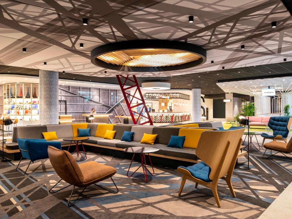 a lobby with a couch and chairs in a building at ibis Paris CDG Airport in Roissy-en-France