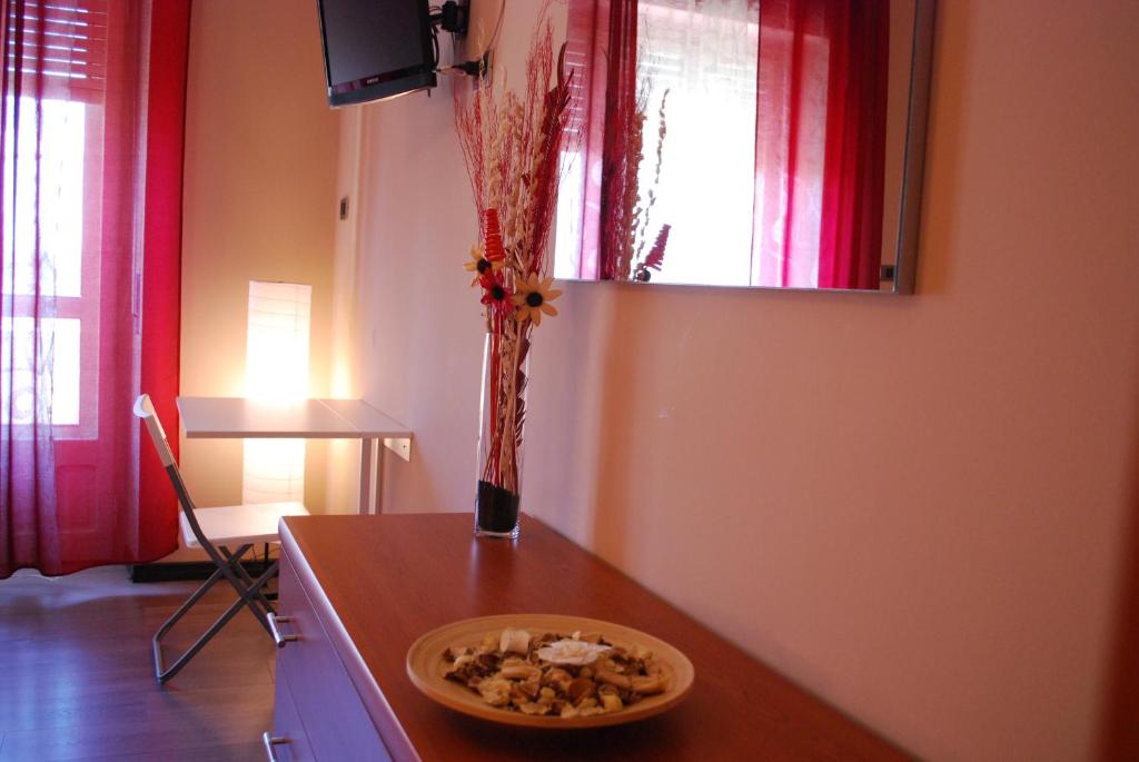 eine Vase Blumen auf einer Theke mit einer Schüssel Essen in der Unterkunft Un Letto a Casteddu in Cagliari