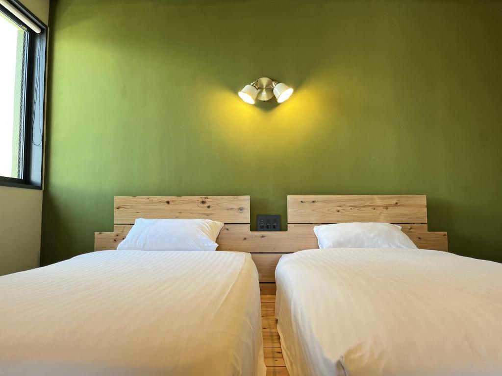 two beds in a room with green walls at The Shore Inn in Chatan