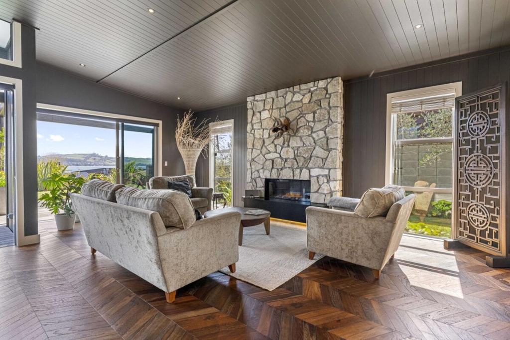 ein Wohnzimmer mit Sofas und einem Steinkamin in der Unterkunft Lake View Lodge in Taupo Airport