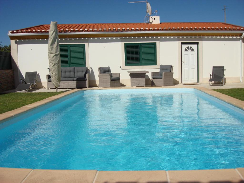 a large blue swimming pool in front of a house at Guest House dos Olivais in Azeitao