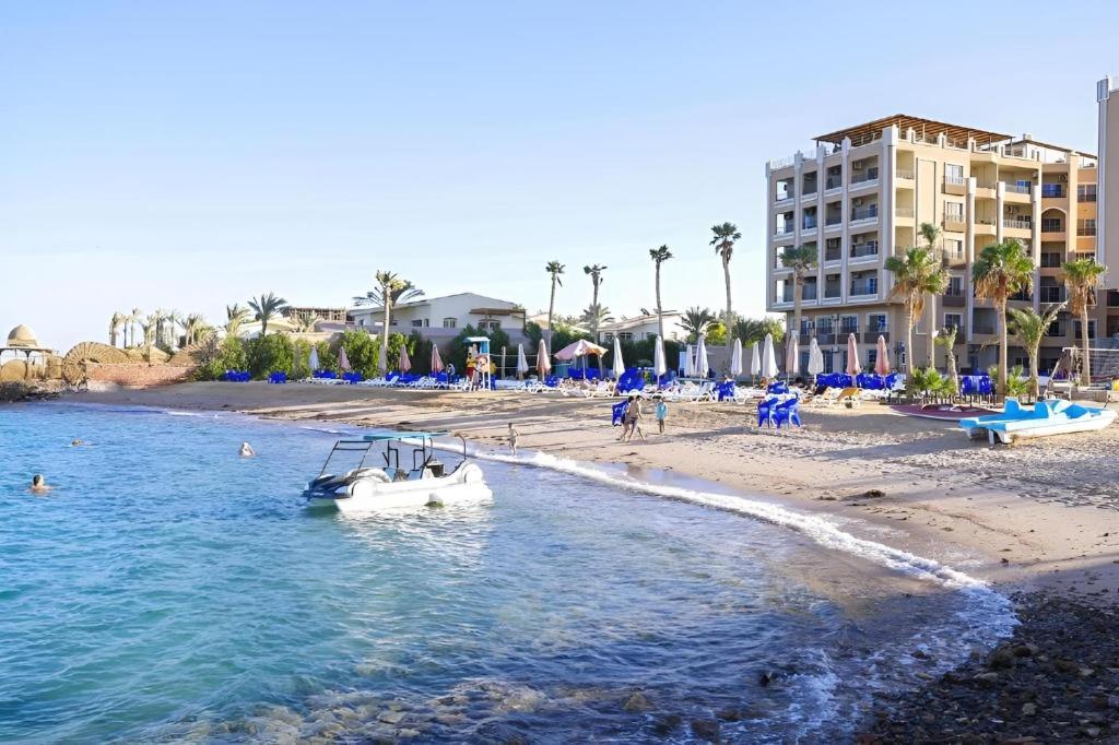 una barca in acqua accanto a una spiaggia di Queen T Juliana Beach Resort a Hurghada
