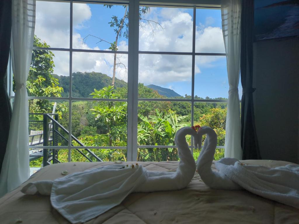 two swans sitting on a bed in front of a window at The Rendezvous Phangan in Ko Phangan