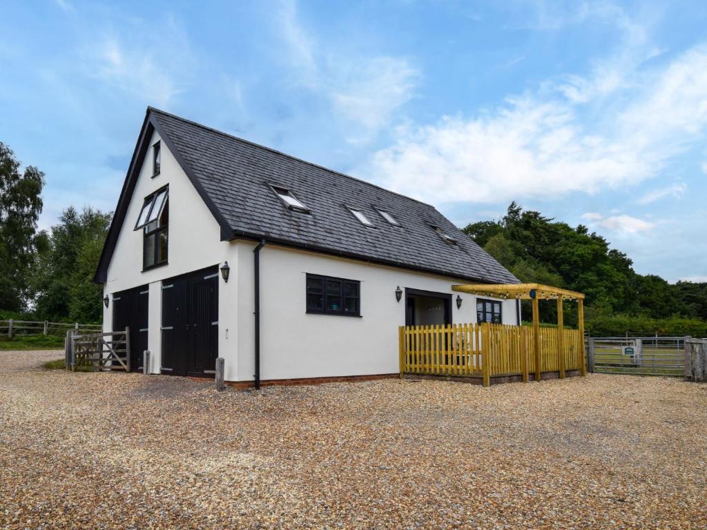 a white barn with a black roof and a fence at 1 Bed in Beaulieu Heath 92943 in Exbury