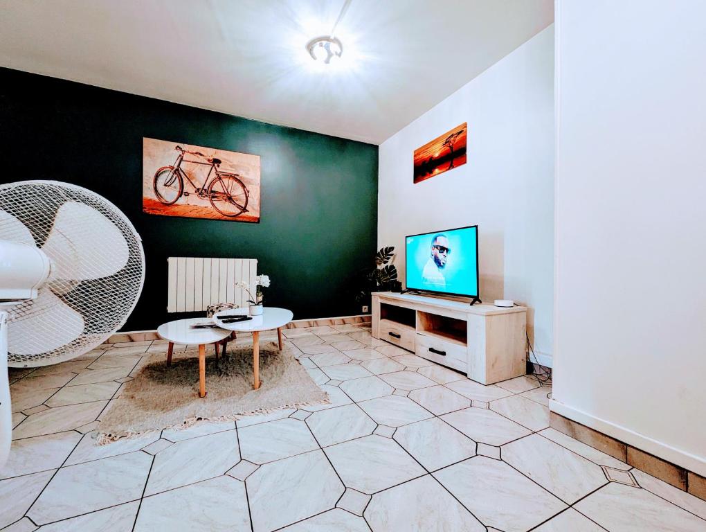 a living room with a tv and a table at Spacious and comfortable apart with terrace in downtown in Evry-Courcouronnes
