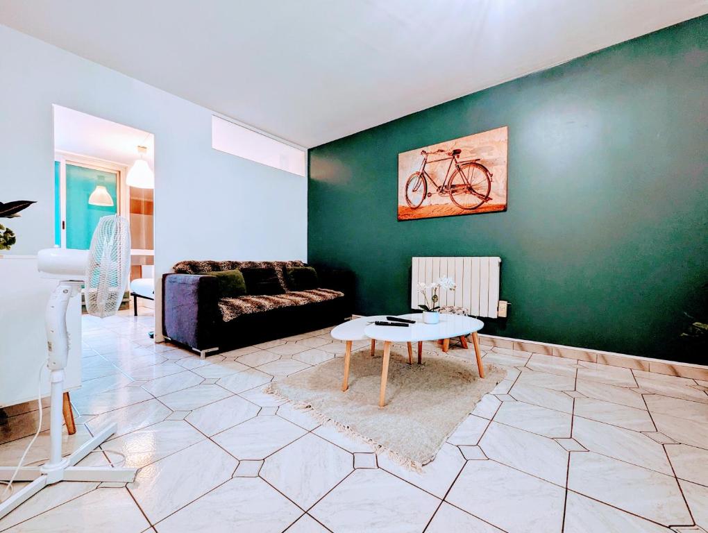 a living room with a green wall with a bike painting at Spacious and comfortable apart with terrace in downtown in Courcouronnes