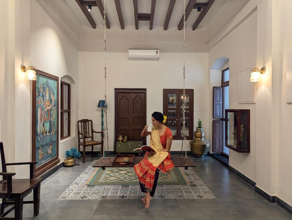 a woman sitting on a swing in a room at Nilayam by LuxUnlock Private Villas in Tiruchchirāppalli