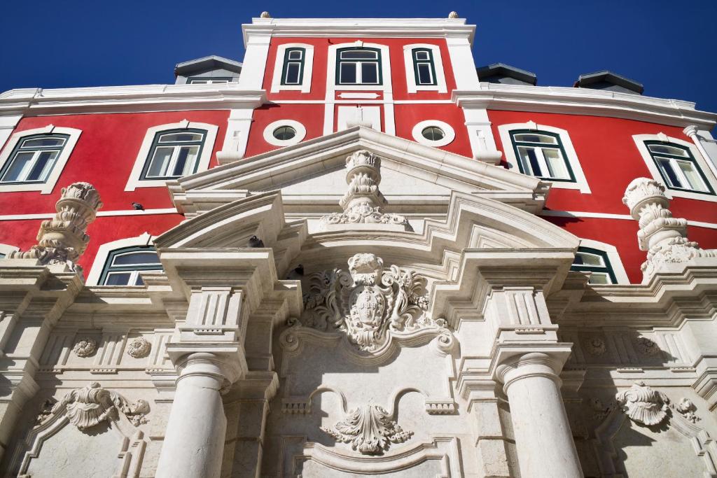 un edificio rosso e bianco con colonne di fronte di Hermitage Castelo - Casa Chafariz a Lisbona