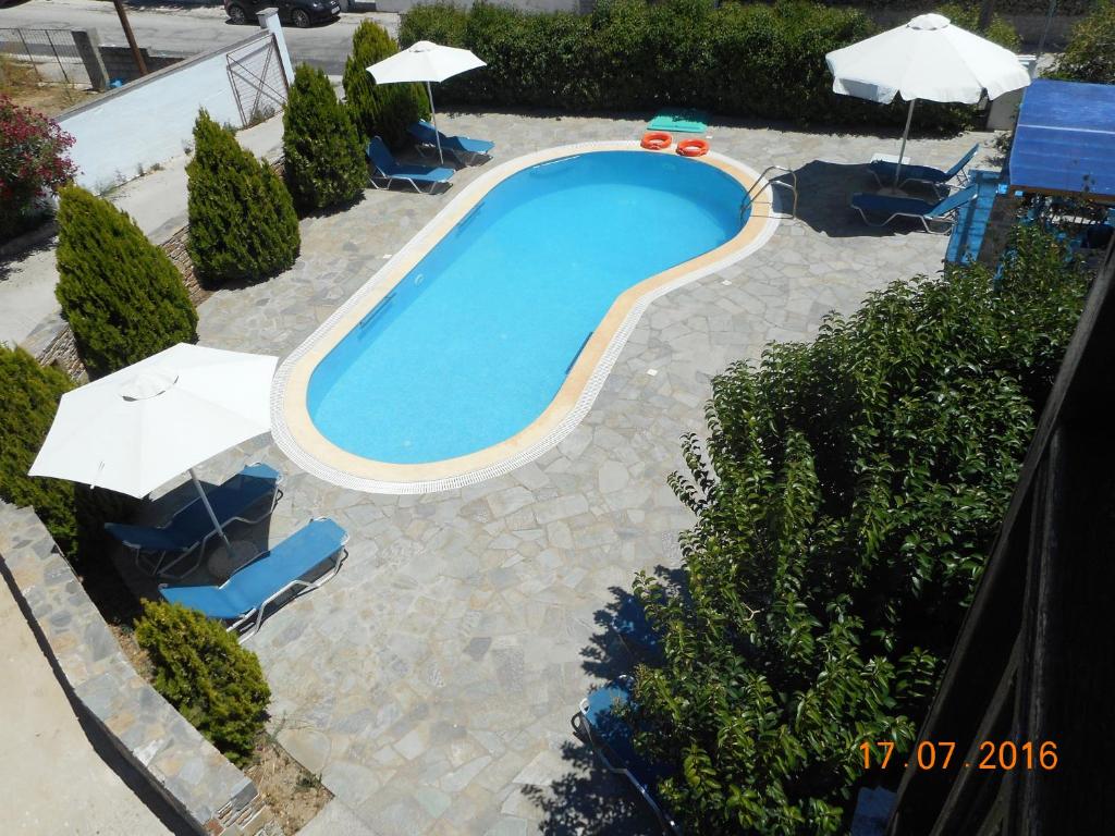 einen Blick über einen Pool mit Stühlen und Sonnenschirmen in der Unterkunft Guesthouse Christos in Skopelos