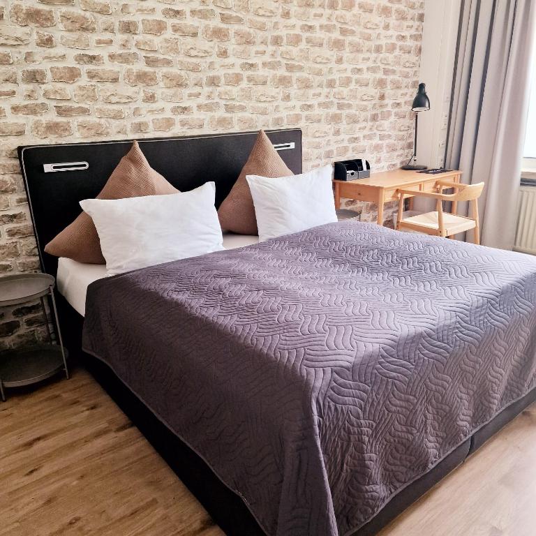 a bedroom with a large bed with a brick wall at Holle - Land Holidays, parterre Ferienwohnung in Lichtenau