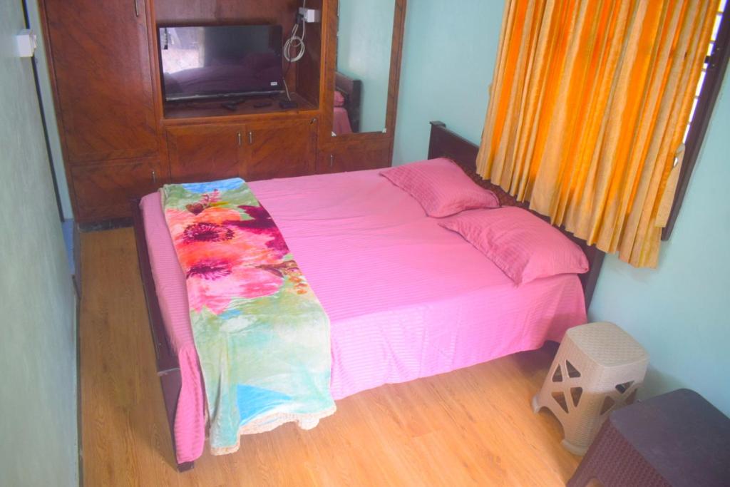 Una cama en una habitación con una manta rosa encima. en Kavitha nest, en Yercaud
