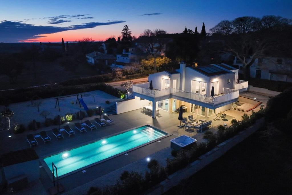 een groot wit huis met een zwembad in de nacht bij Casa Belladonna by Briskva in Višnjan