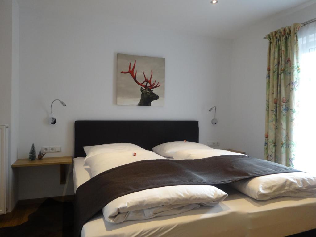 a bedroom with a bed with a deer head on the wall at Pension Rosenhof in Brixen im Thale