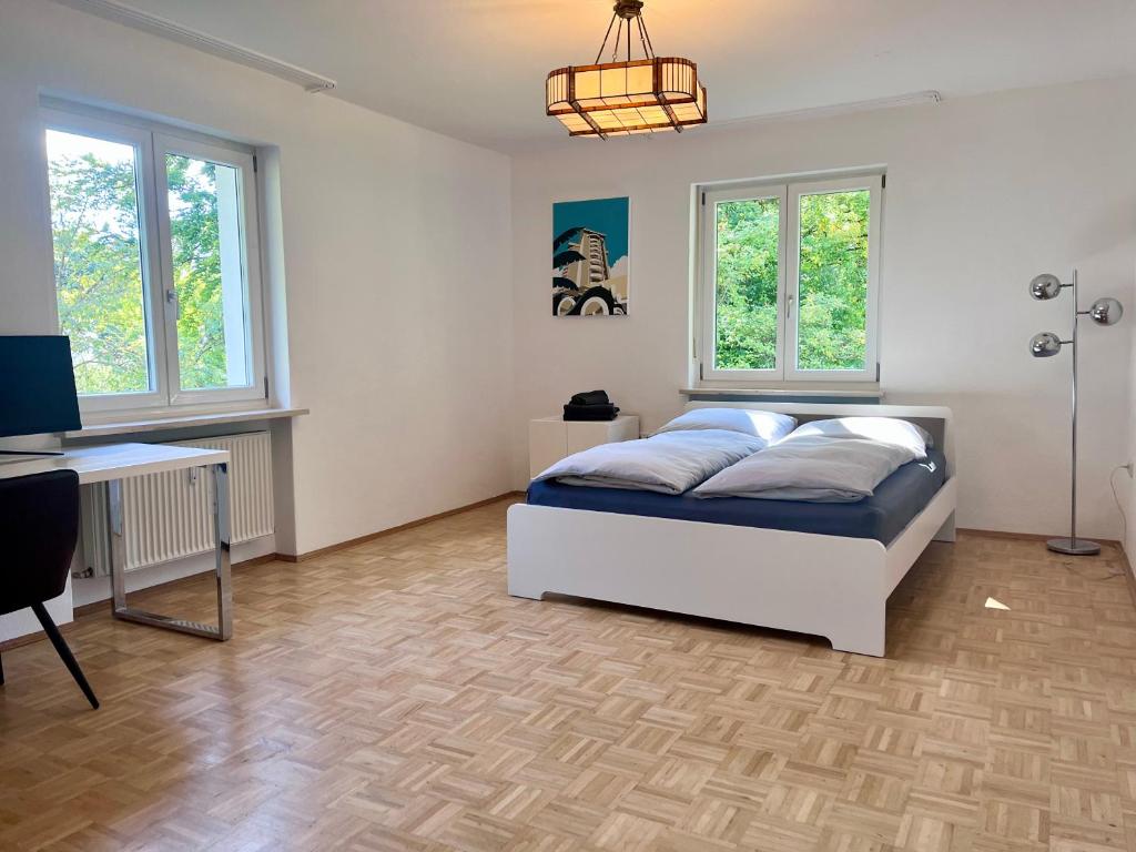 a bedroom with a bed and a desk and windows at Large Munich house with 4 bedrooms in a quiet and greened villa area near Munich in Munich